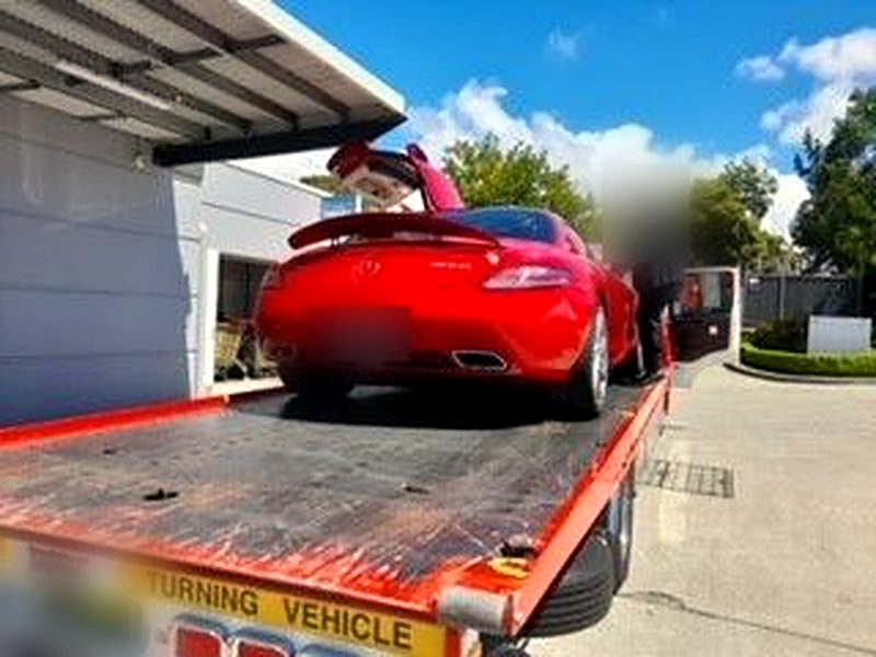 Red Mercedes-Benz SLS being loaded onto a tilt tray from the rear